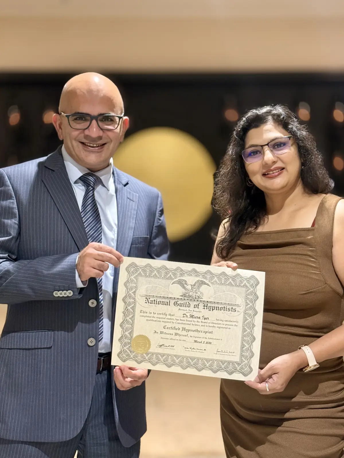 Dr. Maruti Sharma presenting the NGH Certified Hypnotherapist certificate to Dr. Meera Iyer, March 2026